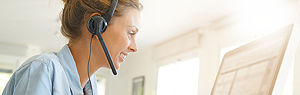 Lächelnde Frau am Computer mit Headset Frau mit Headset lächelt, während sie an einem Computer arbeitet.